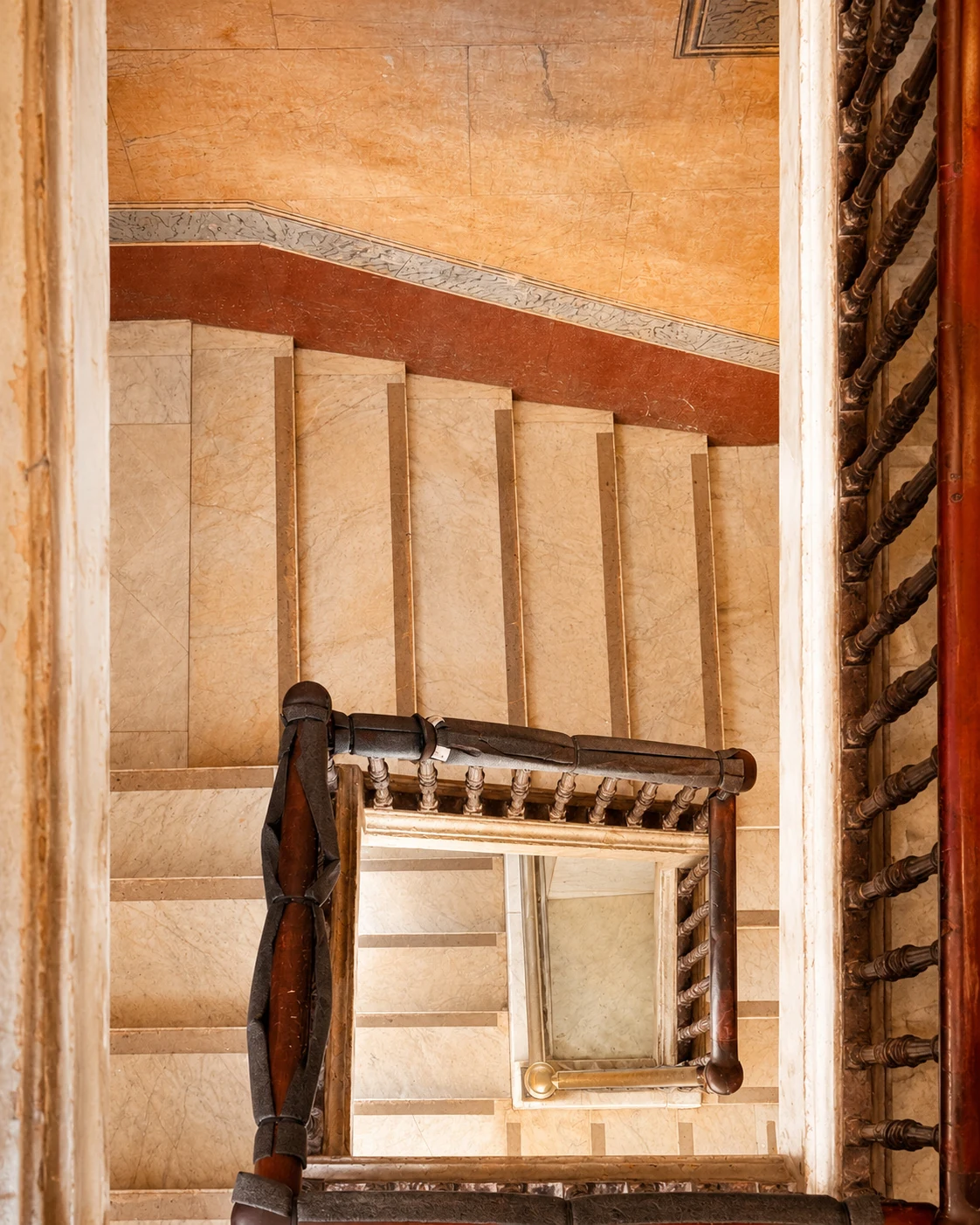 Looking down the marble stairwell at Ambos Mundos through a turned wooden balustrade