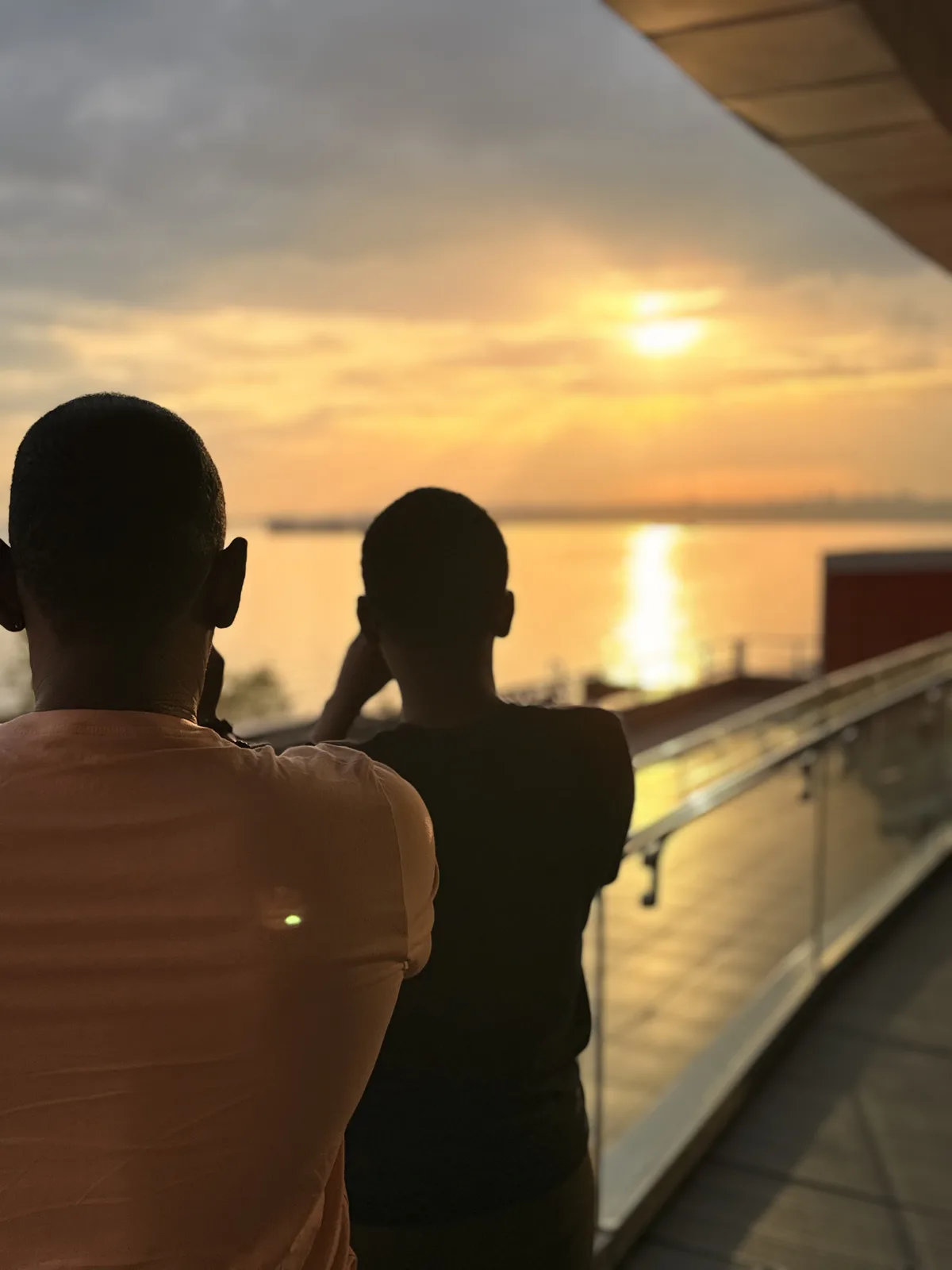 Two figures silhouetted on a terrace watching the sun set over the water in Istanbul