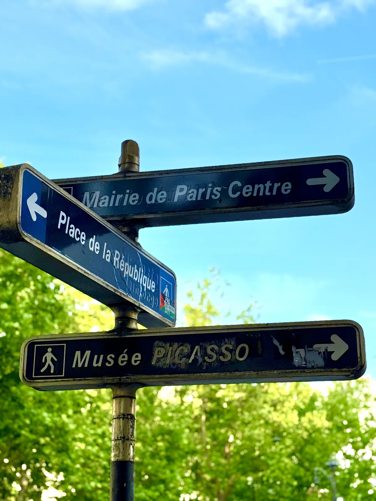 Paris street signs for Place de la République and Musée Picasso against a bright blue sky