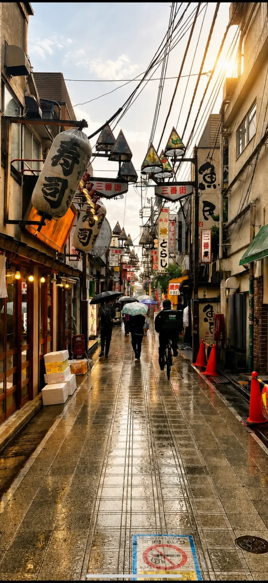 Rain-slicked Tokyo backstreet lined with lanterns and hanging signage, figures walking away under umbrellas