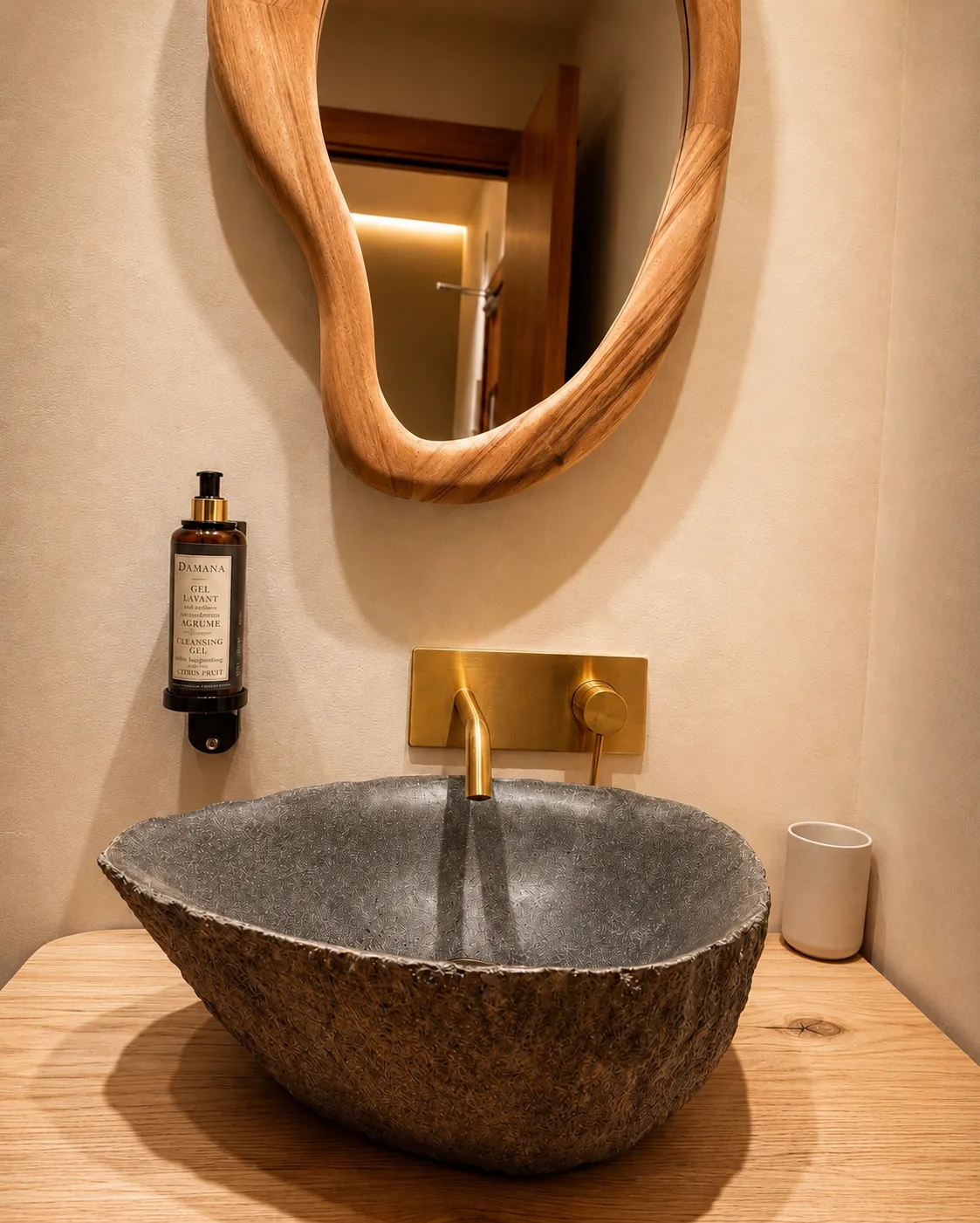 Carved stone basin, organic-shaped mirror and brass tap in an Ambos Mundos bathroom