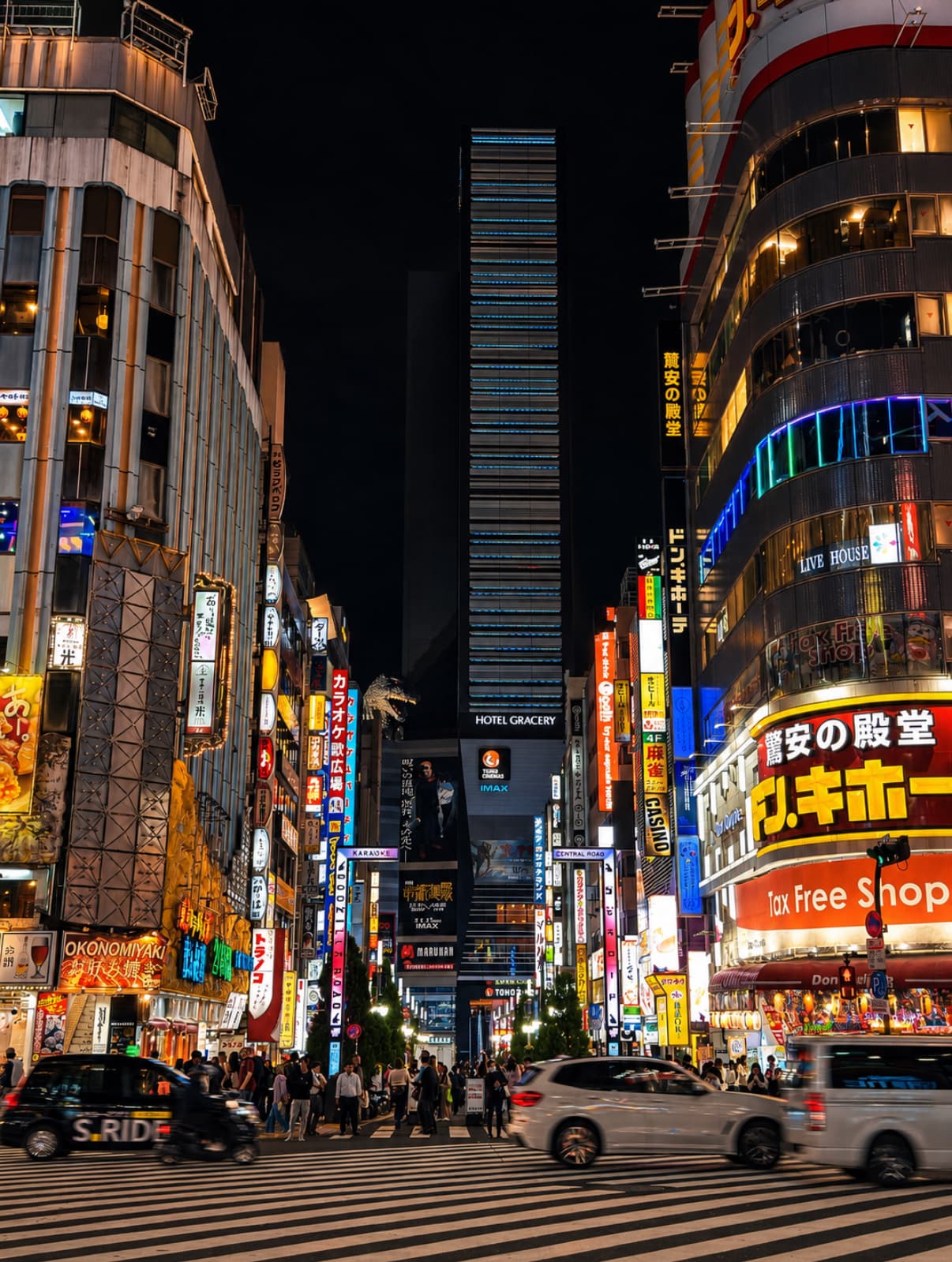 Shinjuku at night, layered neon signage above a crowded Tokyo street