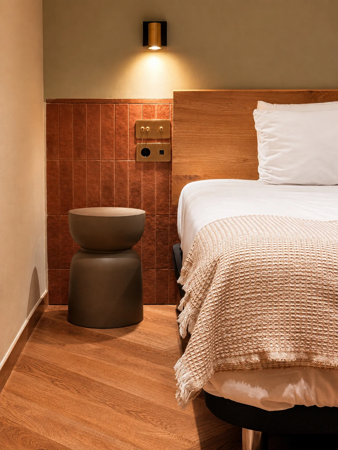 Bedside detail at Ambos Mundos: terracotta tiling, brass switches and a sculptural side table beside the bed