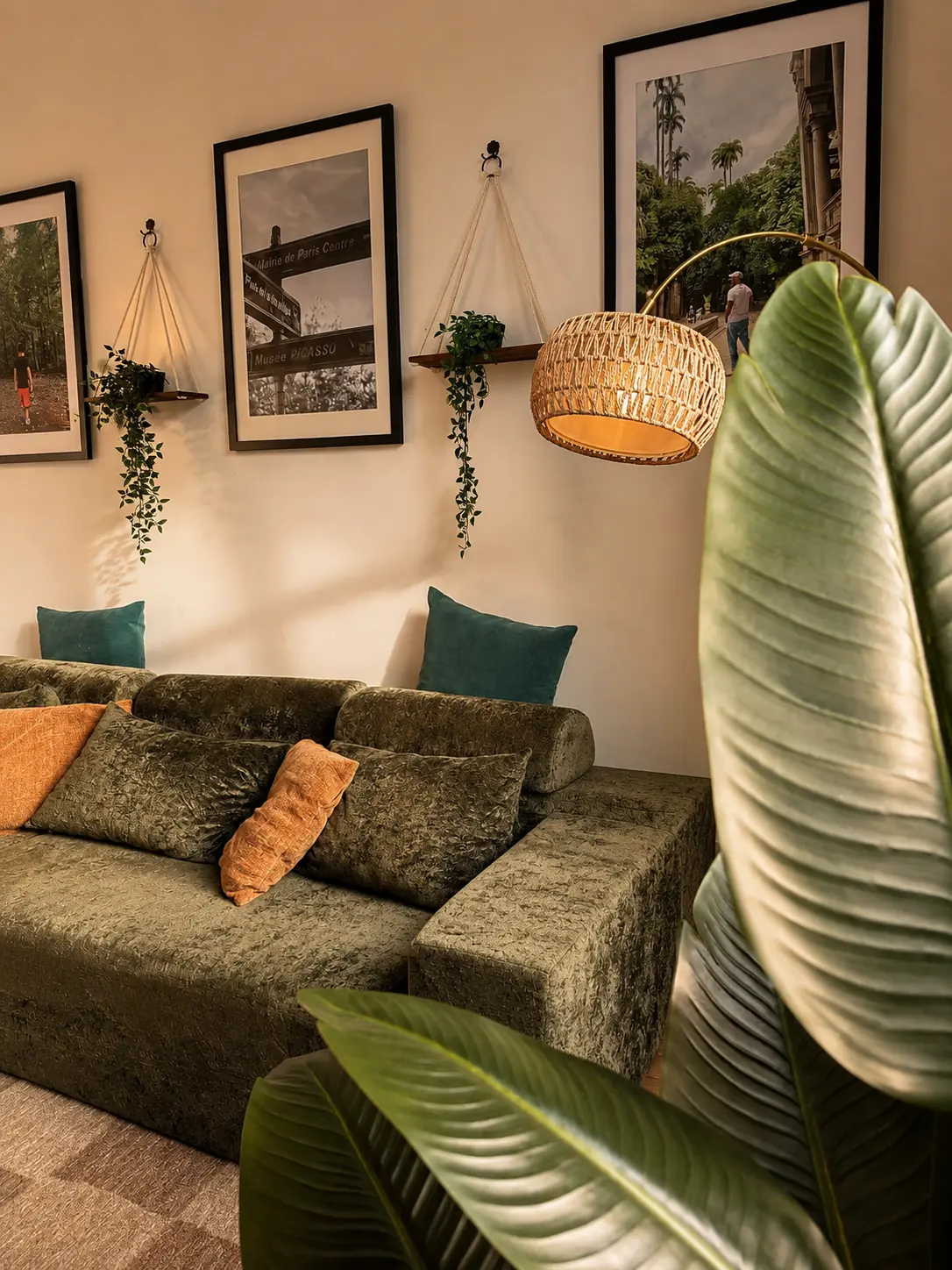 Green velvet seating beneath layered wall art and a hanging plant at Alexander Residence