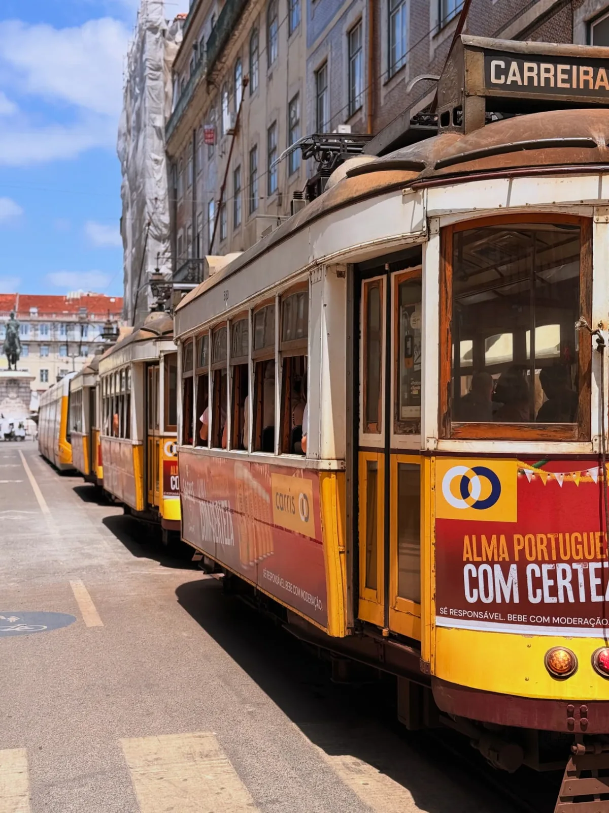 A yellow tram climbing a narrow Lisbon street between pale buildings