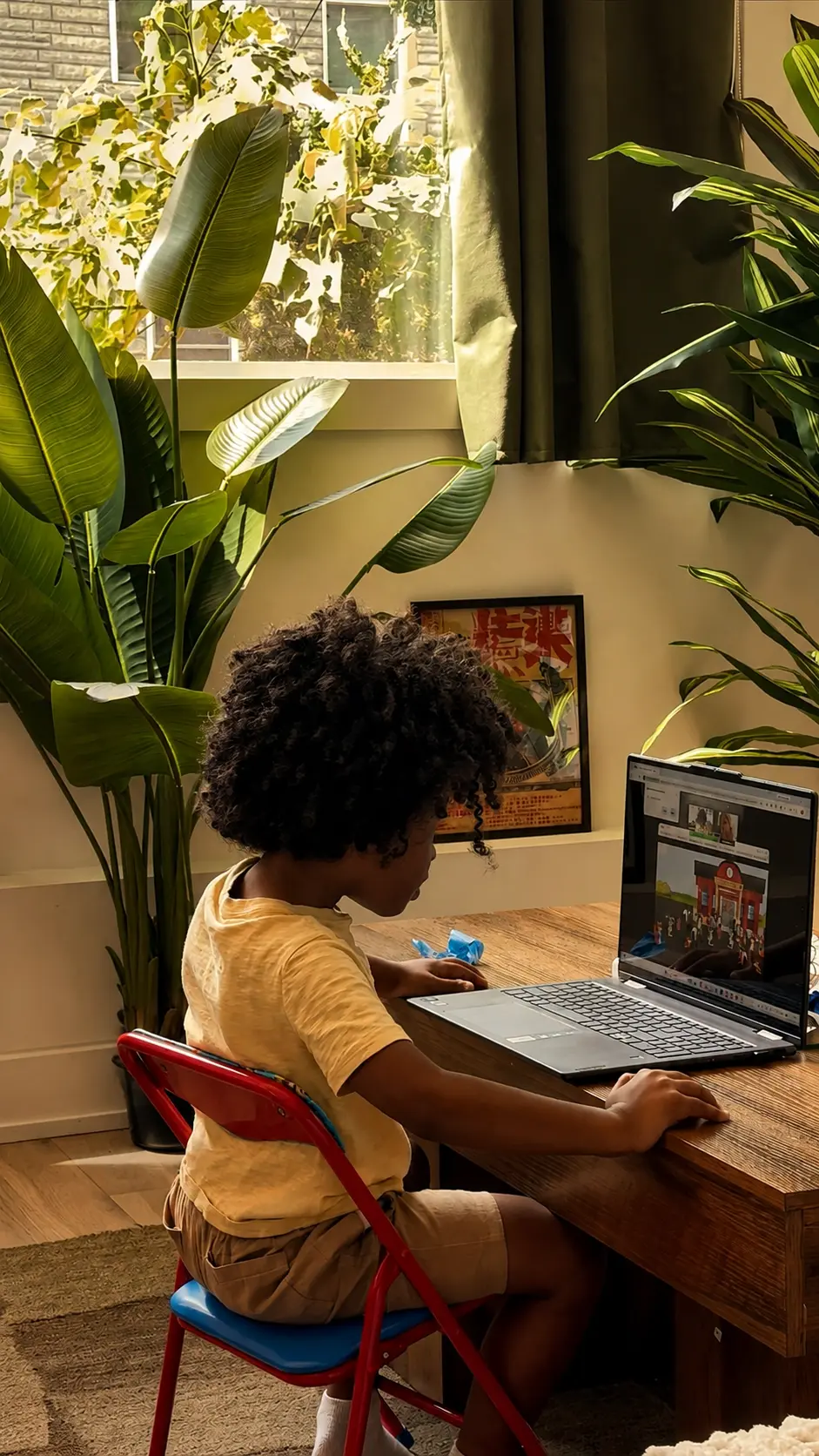 A person working at the desk in the living space at Alexander Residence, framed by large plants